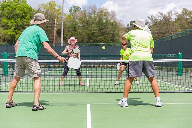 Four senior citizens playing pickleball.
